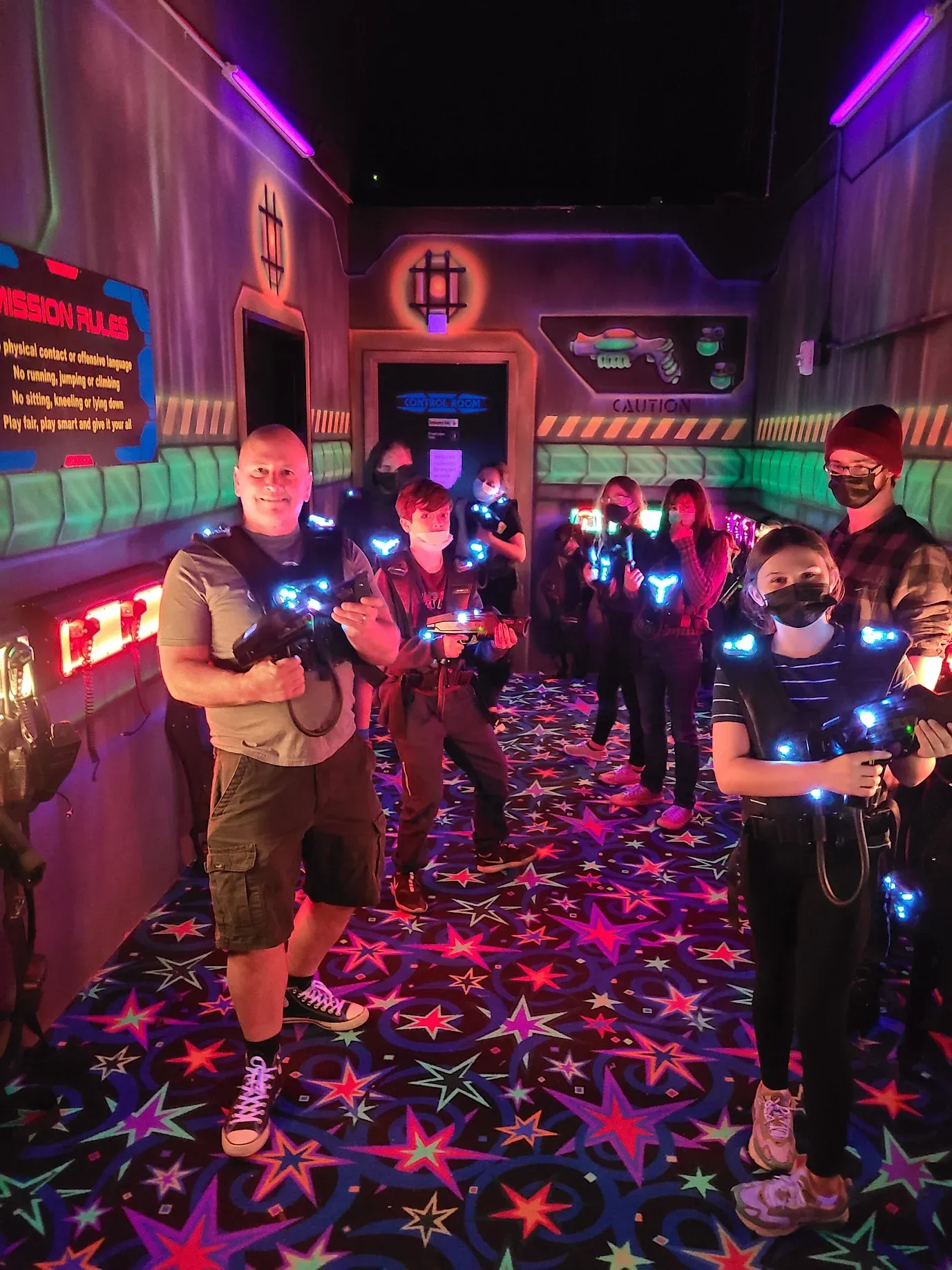 Group of friends wearing laser tag vests in a neon-lit arena